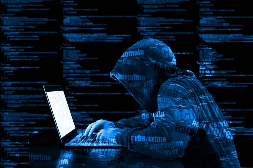 A hacker in a blue hoody with cyber security threats printed all over him.