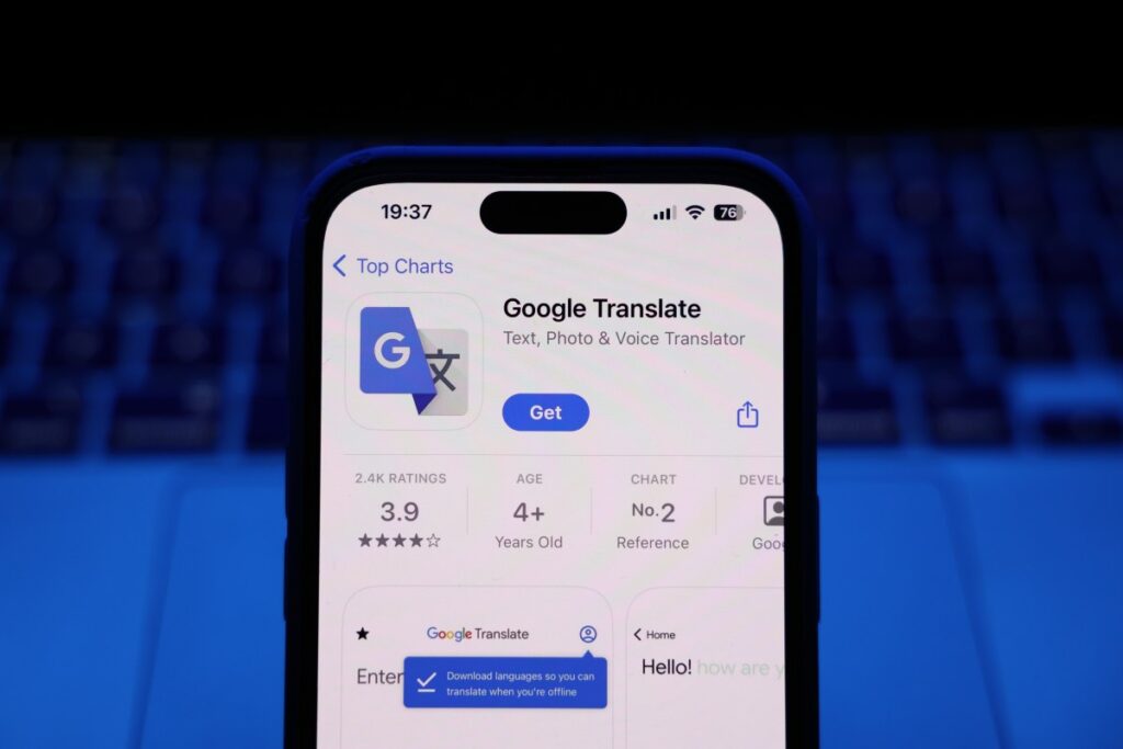 A laptop keyboard and Google Translate on App Store displayed on a phone screen are seen in this illustration photo