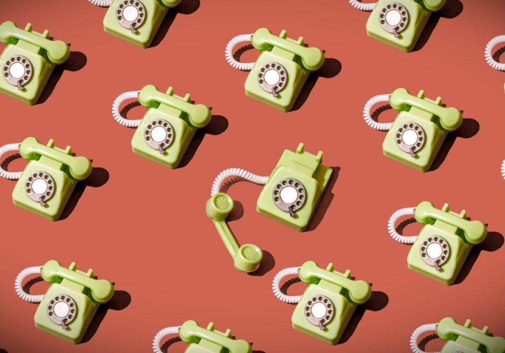 High angle view of some vintage green rotary telephones arranged on a brown background, showcasing retro communication technology with a nostalgic and artistic flair